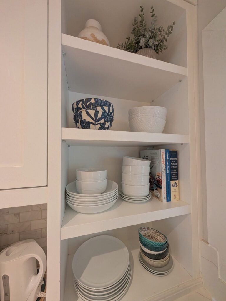 Real client kitchen shelves styled with the homeowner's dishes, patterned bowls, books, vase and greenery by Liz Organizes Your Pretty Mess