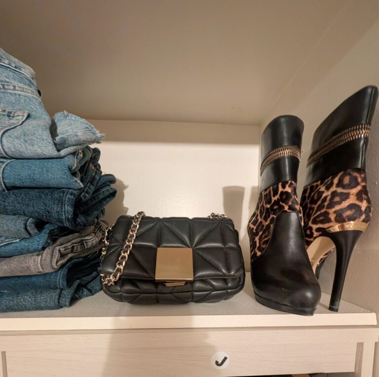 Luxury closet shelf styled with folded jeans, black quilted handbag and leopard-print ankle boots